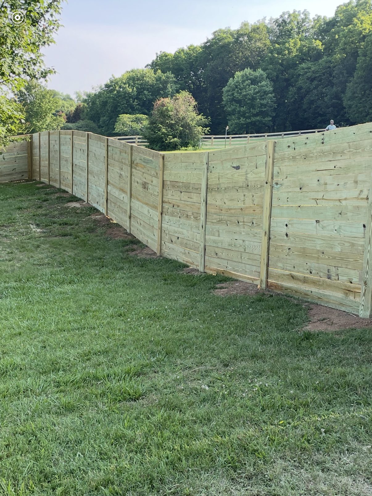 Horizontal board wood privacy fence running along a large backyard