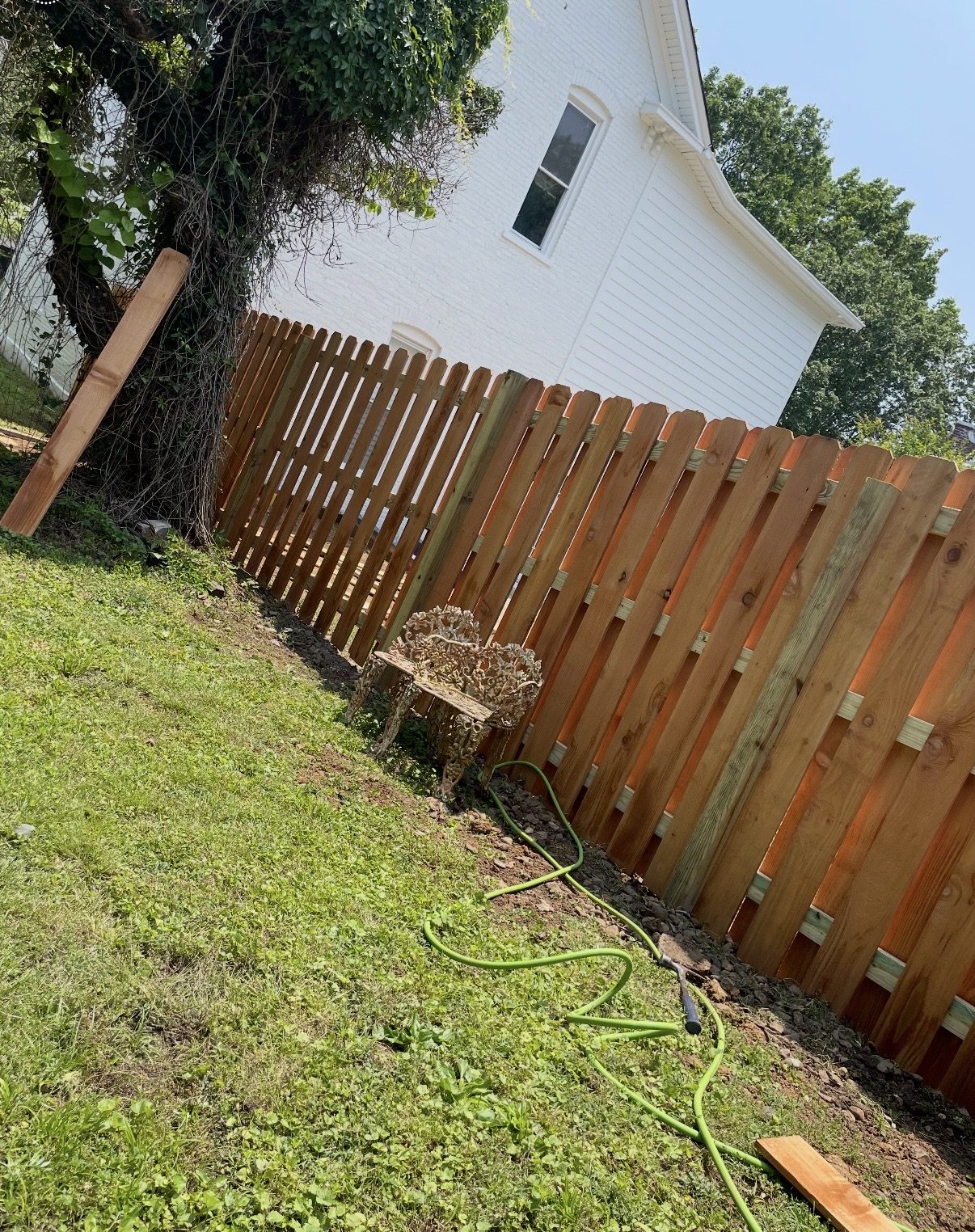 Shadowbox-style wood privacy fence beside a white brick house